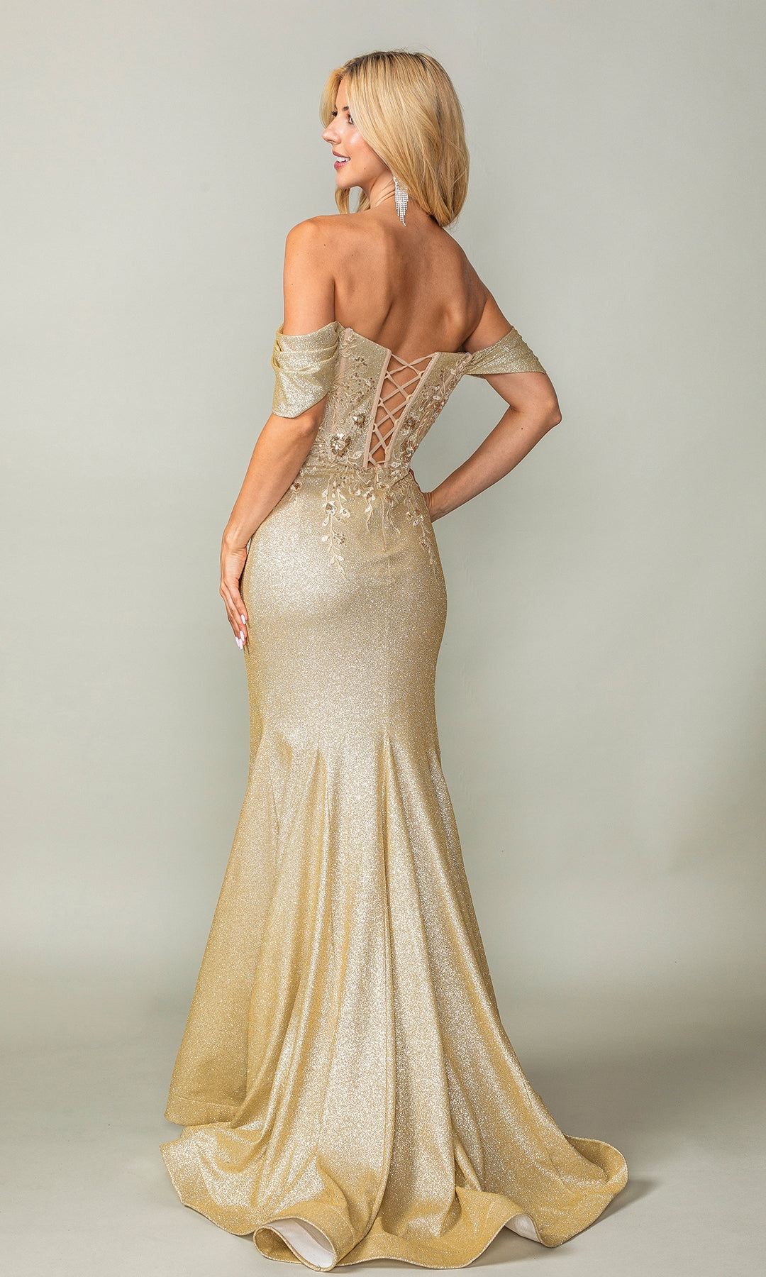 Woman in the Dancing Queen 4362 Off-Shoulder Long Prom Dress, a floor-length gold shimmer gown with a mermaid silhouette and lace-up back, stands and looks over her shoulder.